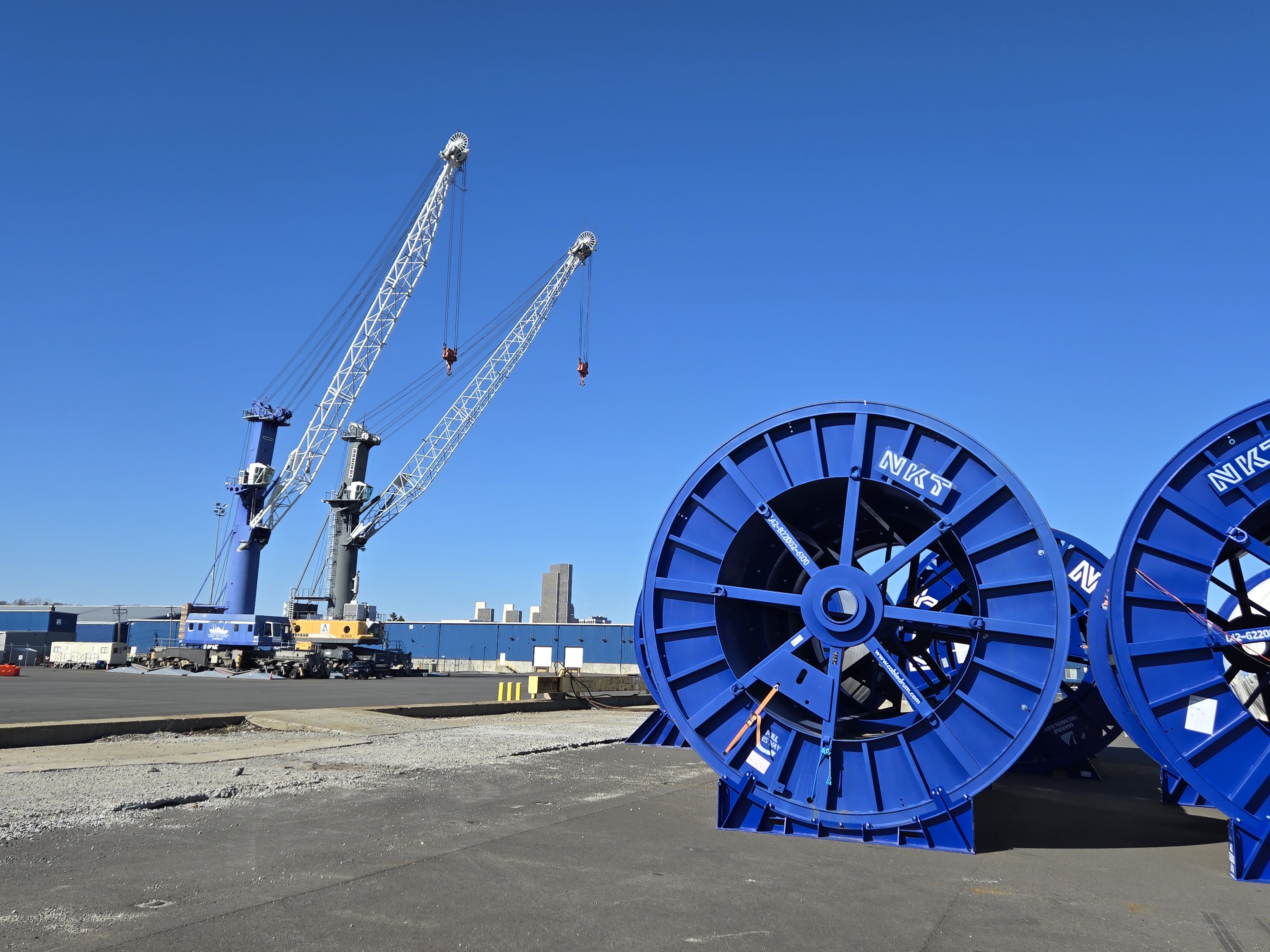Two cranes and two large blue rolls against a blue sky
