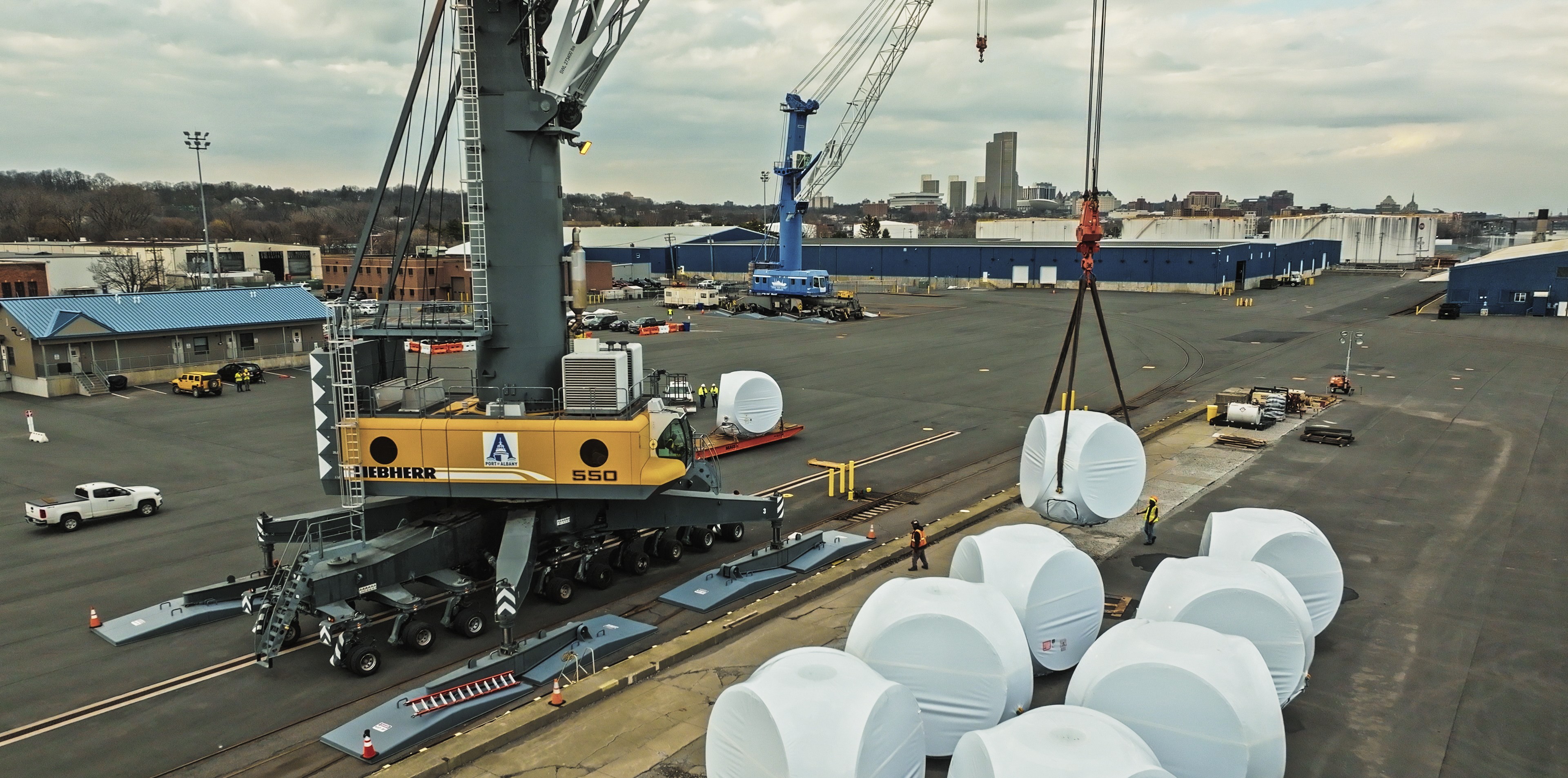Port crane lift onshore wind component with Albany city skyline in the background