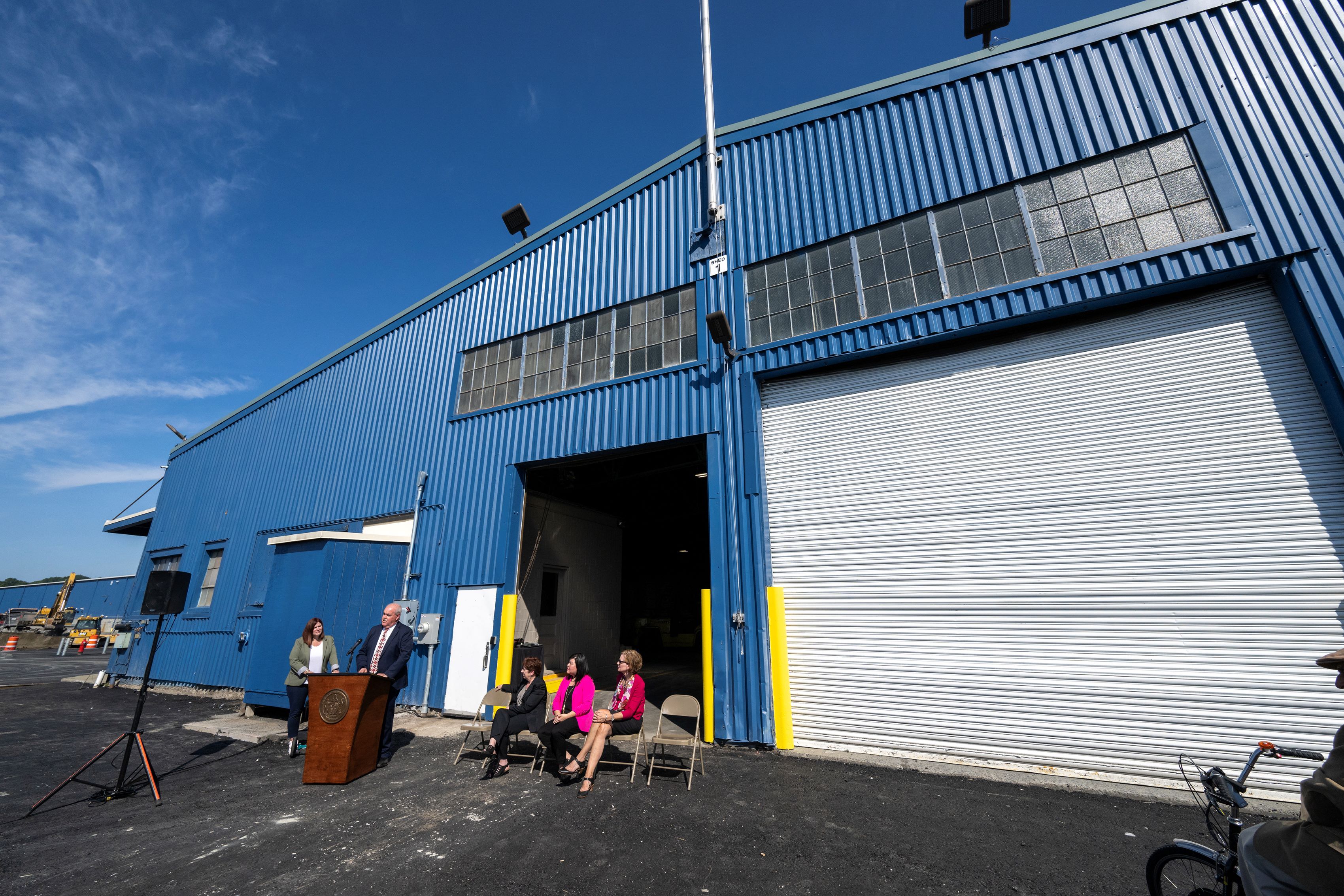 A large blue warehouse shed with a podium in front. 