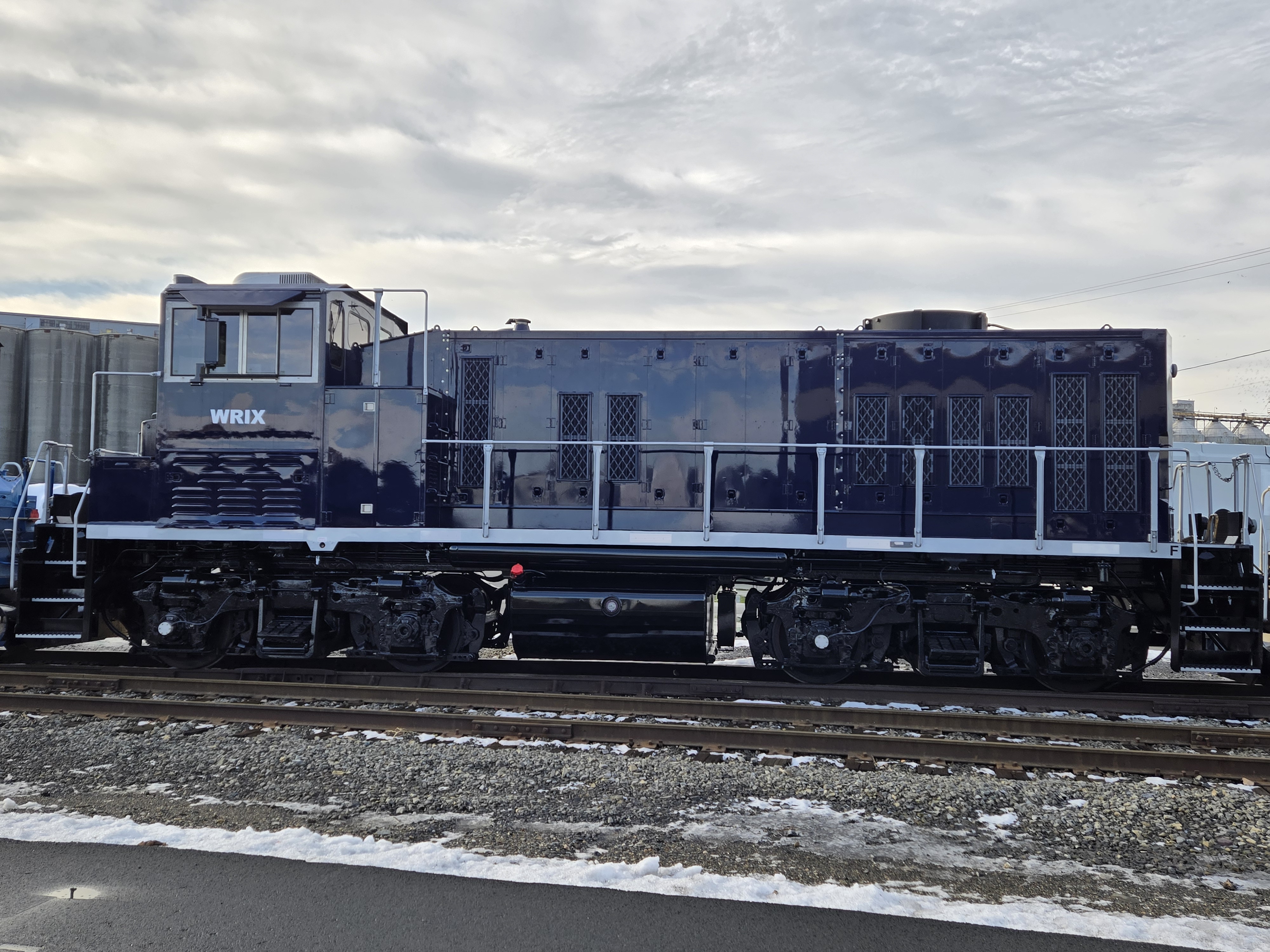 dark blue locomotive with silver accents under cloudy sky