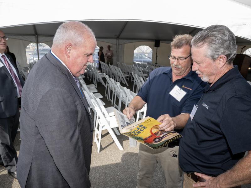 Port CEO Rich Hendrick looks on as Ardent Mills Sean Gager shares 1932 Popular Science issue with Logistec's Bill Ring