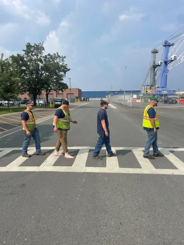 Four staff members crossing Smith Blvd evoking the album cover art from the Beatles' Abbey Road Port Fab Four