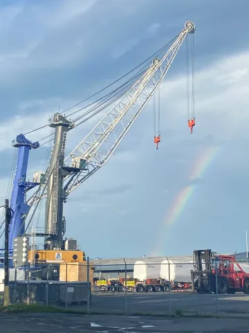 Two mobile harbor cranes with rainbow in the background 