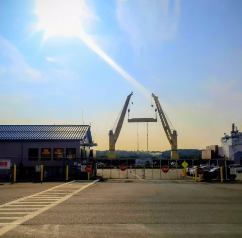 View of cranes during combined lift at the dock on a sunny day