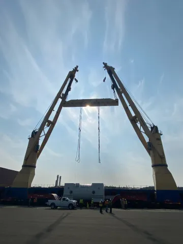 cranes, backlit by the sun, working on combined lift
