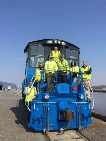 Albany Port Railroad team, in safety yellow, standing on the stairs of the locomotive