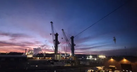 dramatic sunrise behind ship and cranes 