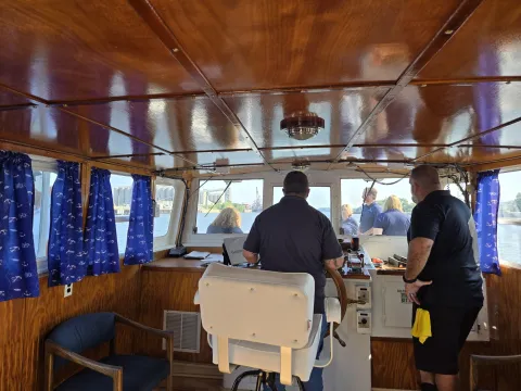 Piloting the Spirit of Albany as seen from the inside of the cabin, with staff on the bow