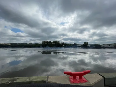 gray clouds reflected on the Hudson River with red bollard in the foreground