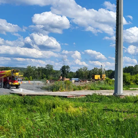 Utility pole in the foreground with approaching cement truck to pour adjacent substation support