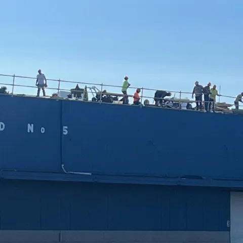 Workers in silhouette on the roof of Shed 5