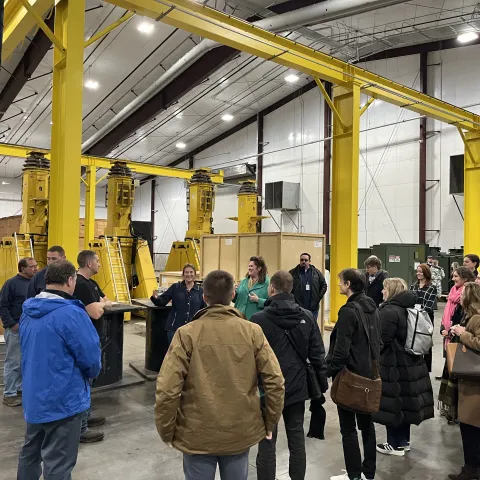 a group of people from GASCN in a warehouse with large yellow gantry crane