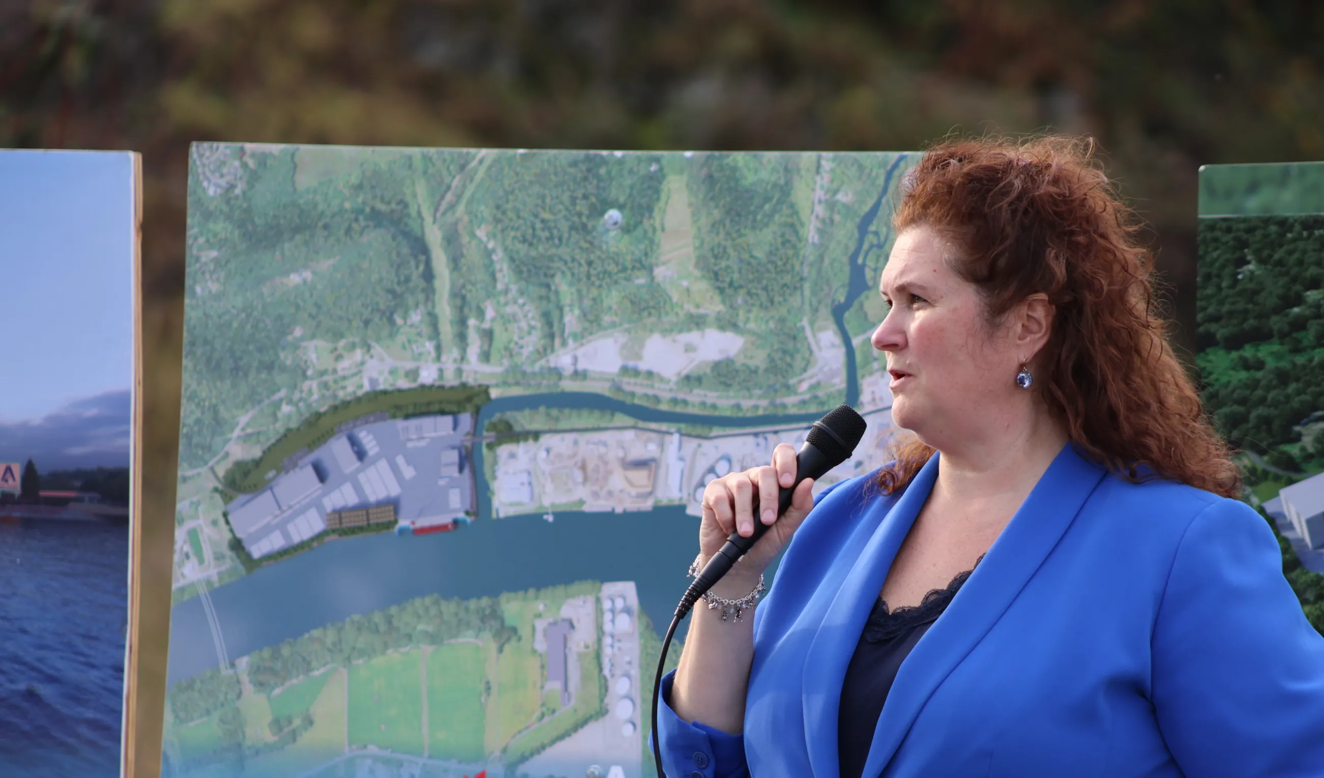 Megan Daly stands in front of poster boards holding a microphone