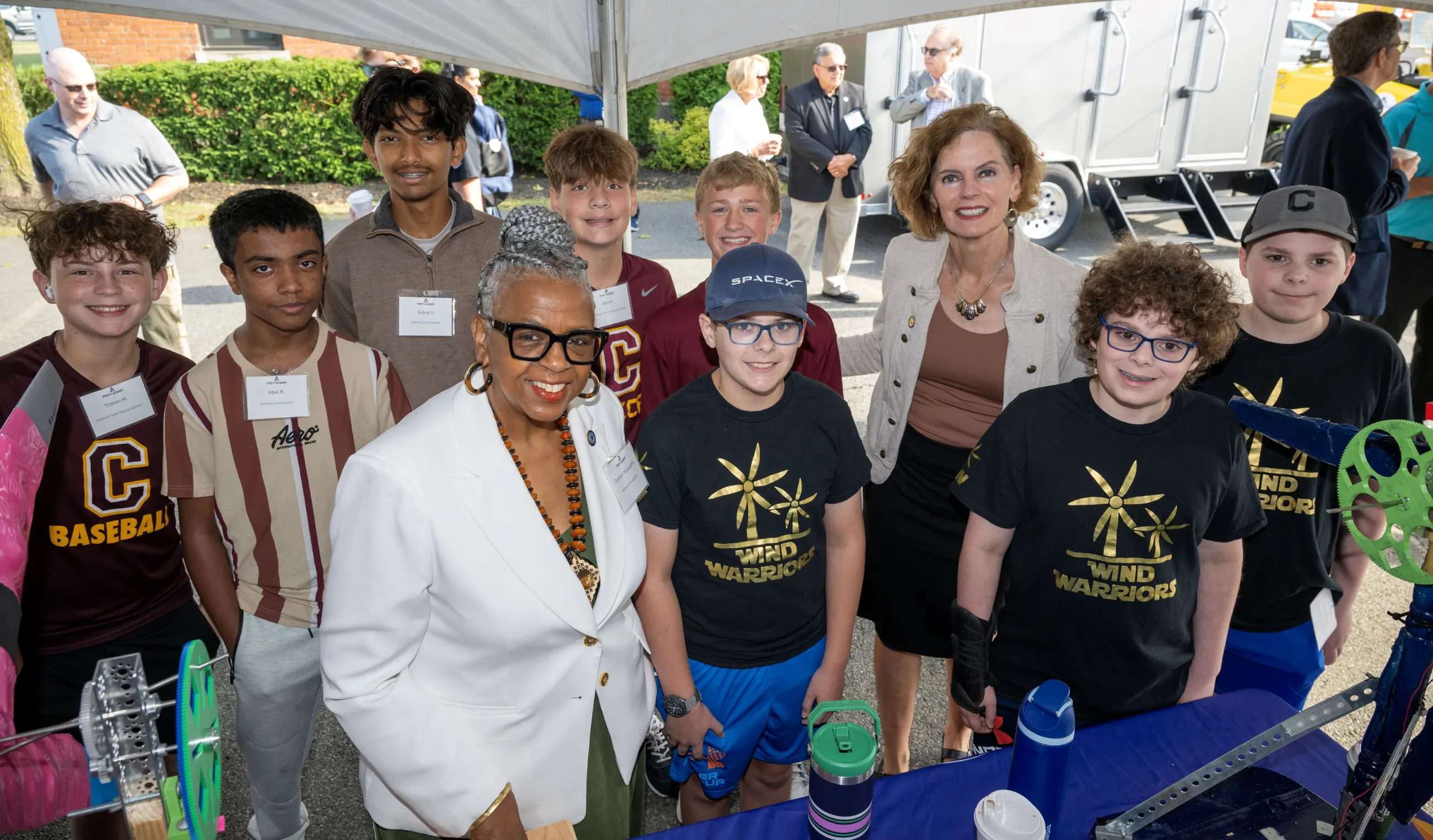 Smiling group of kids and Port workers under a tent outside