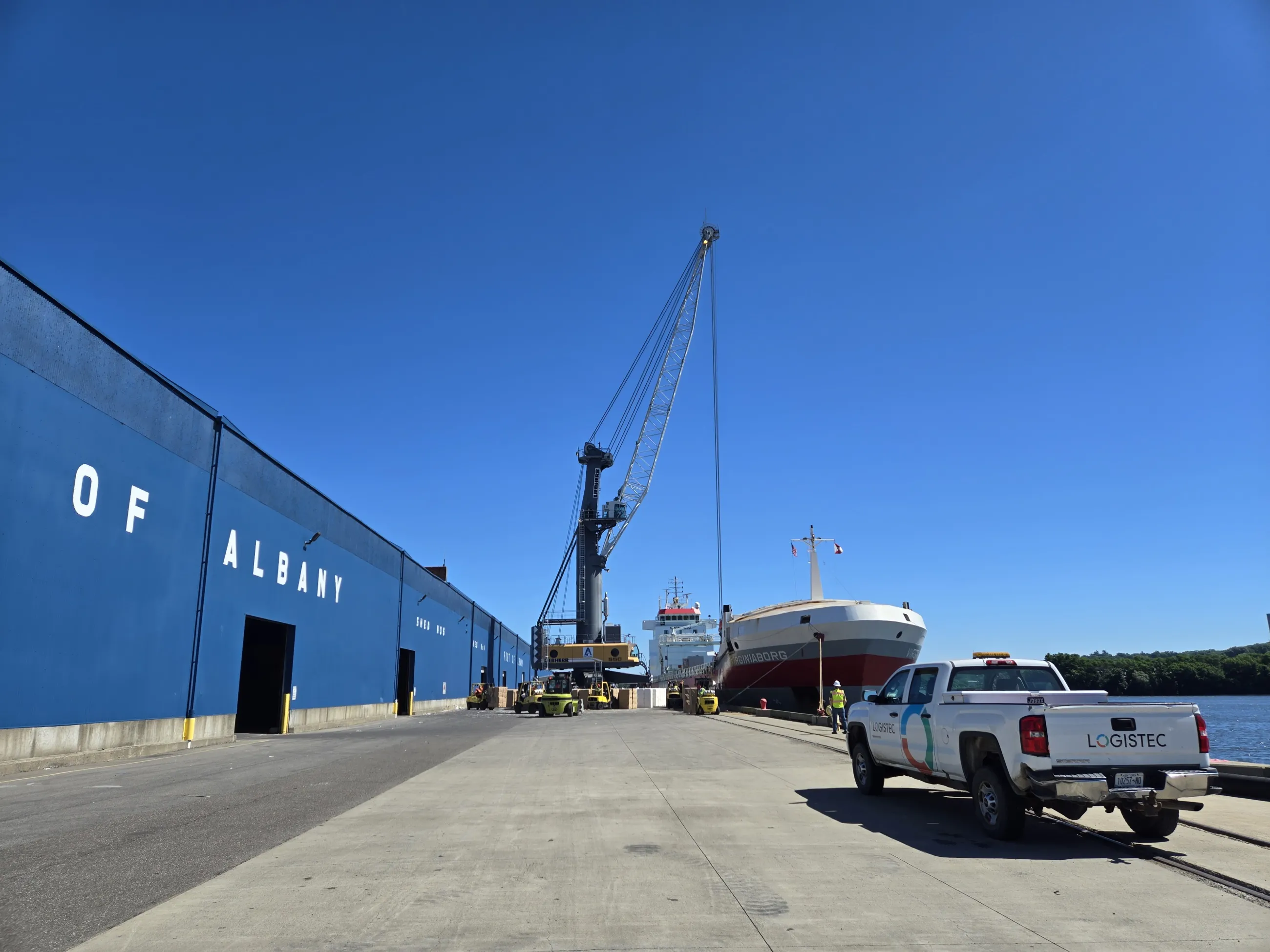Wide view of a crane unloading from a boat next to a shed