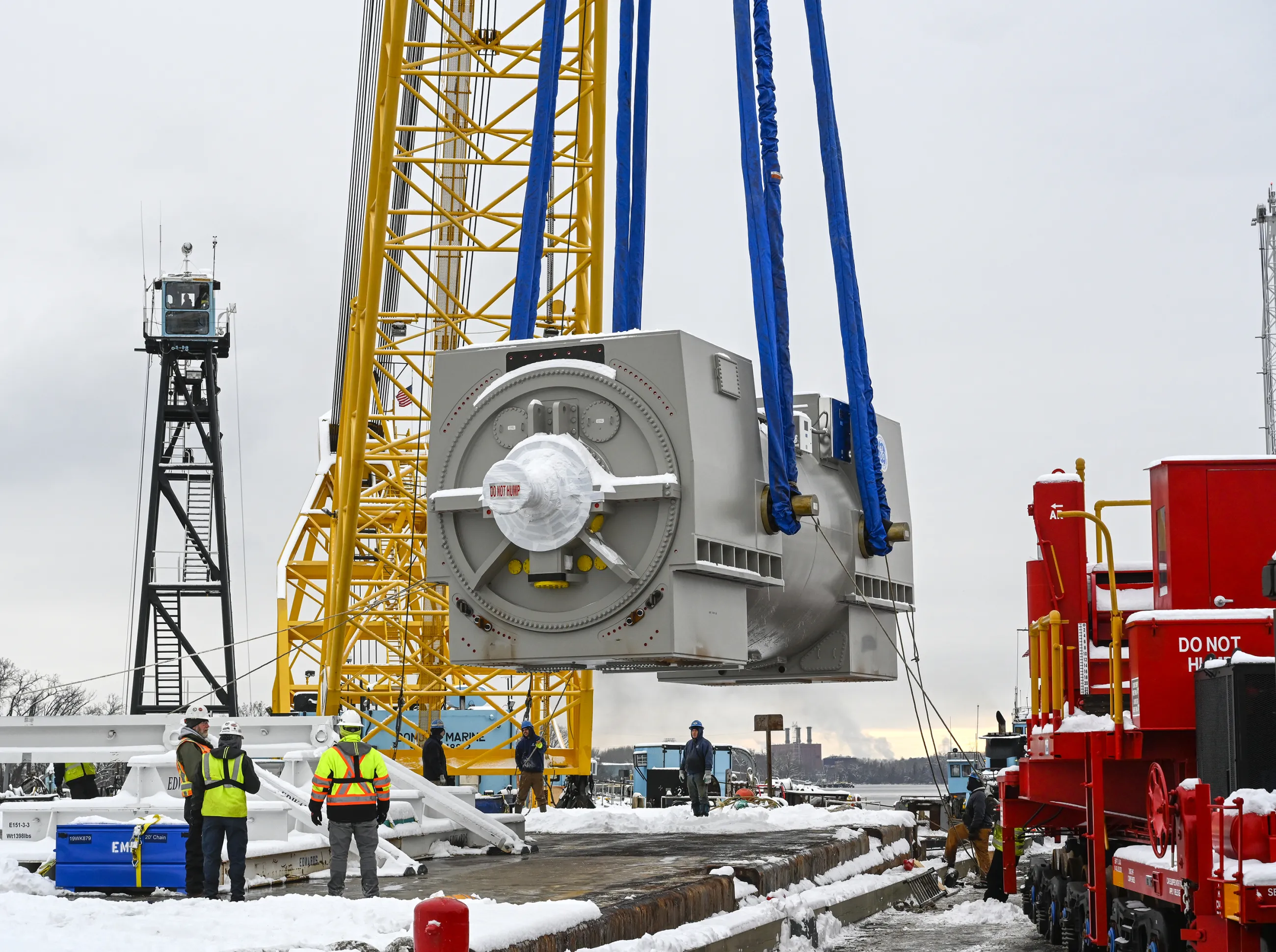 Heavy lift of transformer, with workers in safety gear in winter/snow 