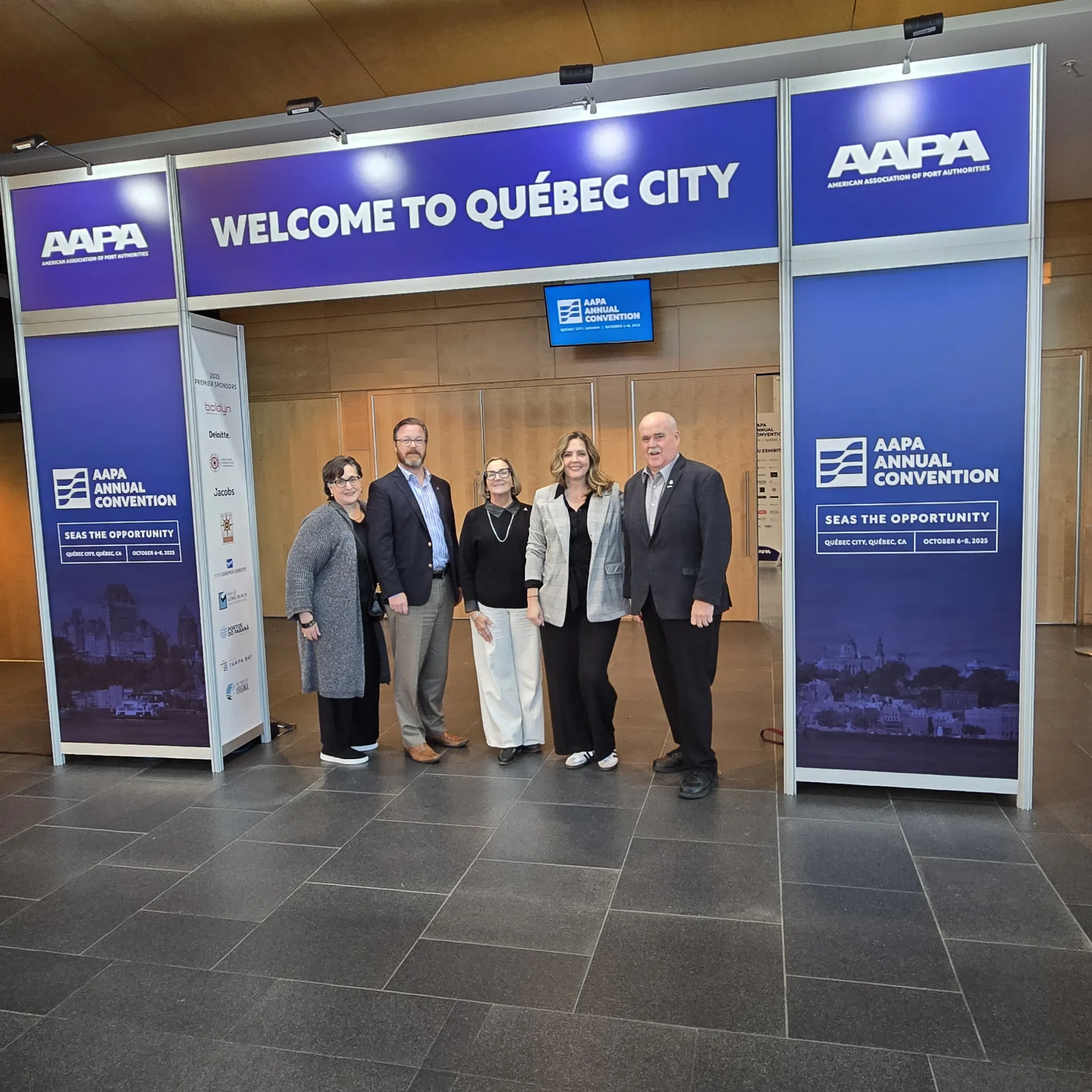 Five Port staff members under convention Welcome arch