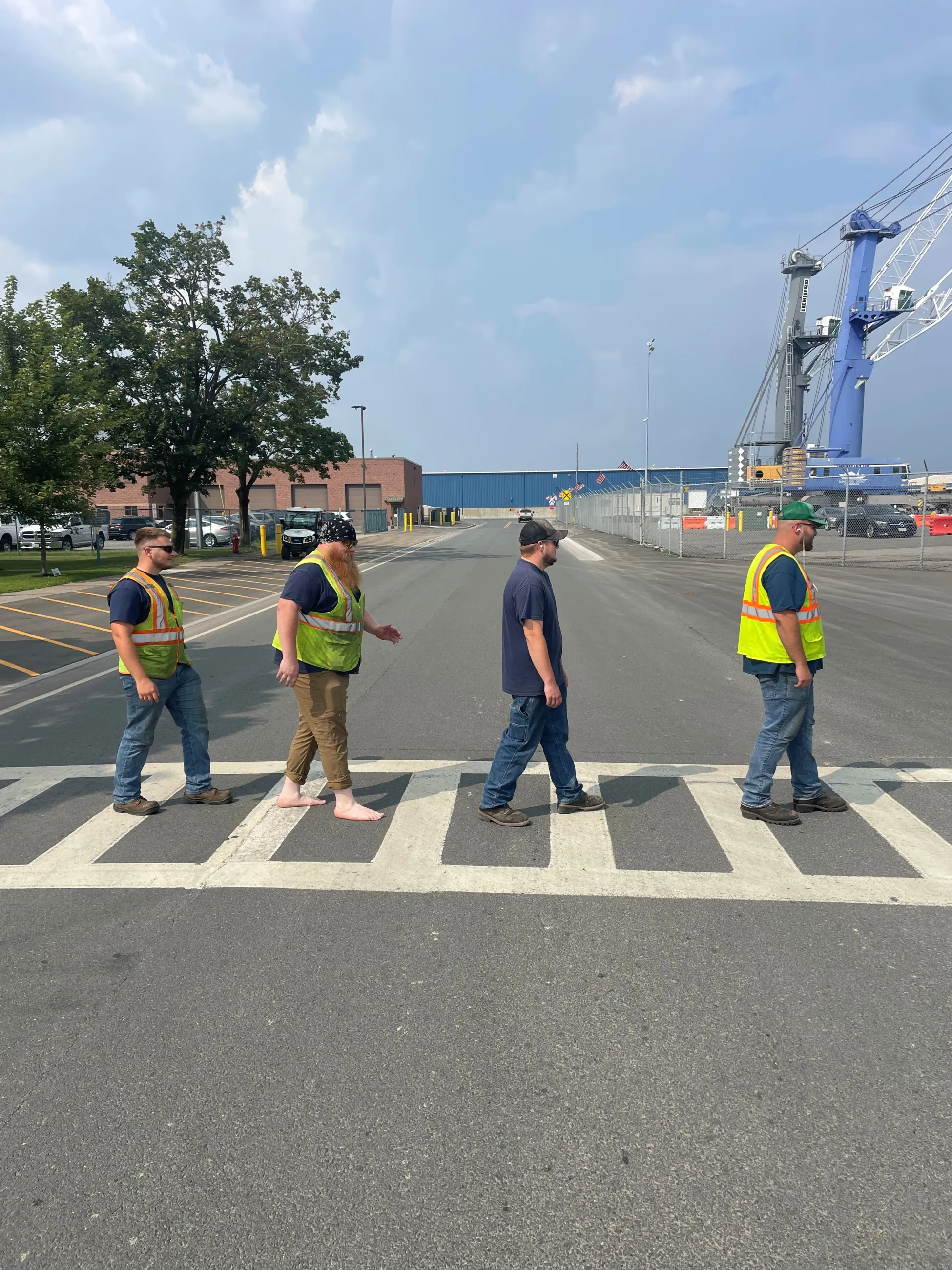 Four staff members crossing Smith Blvd evoking the album cover art from the Beatles' Abbey Road Port Fab Four