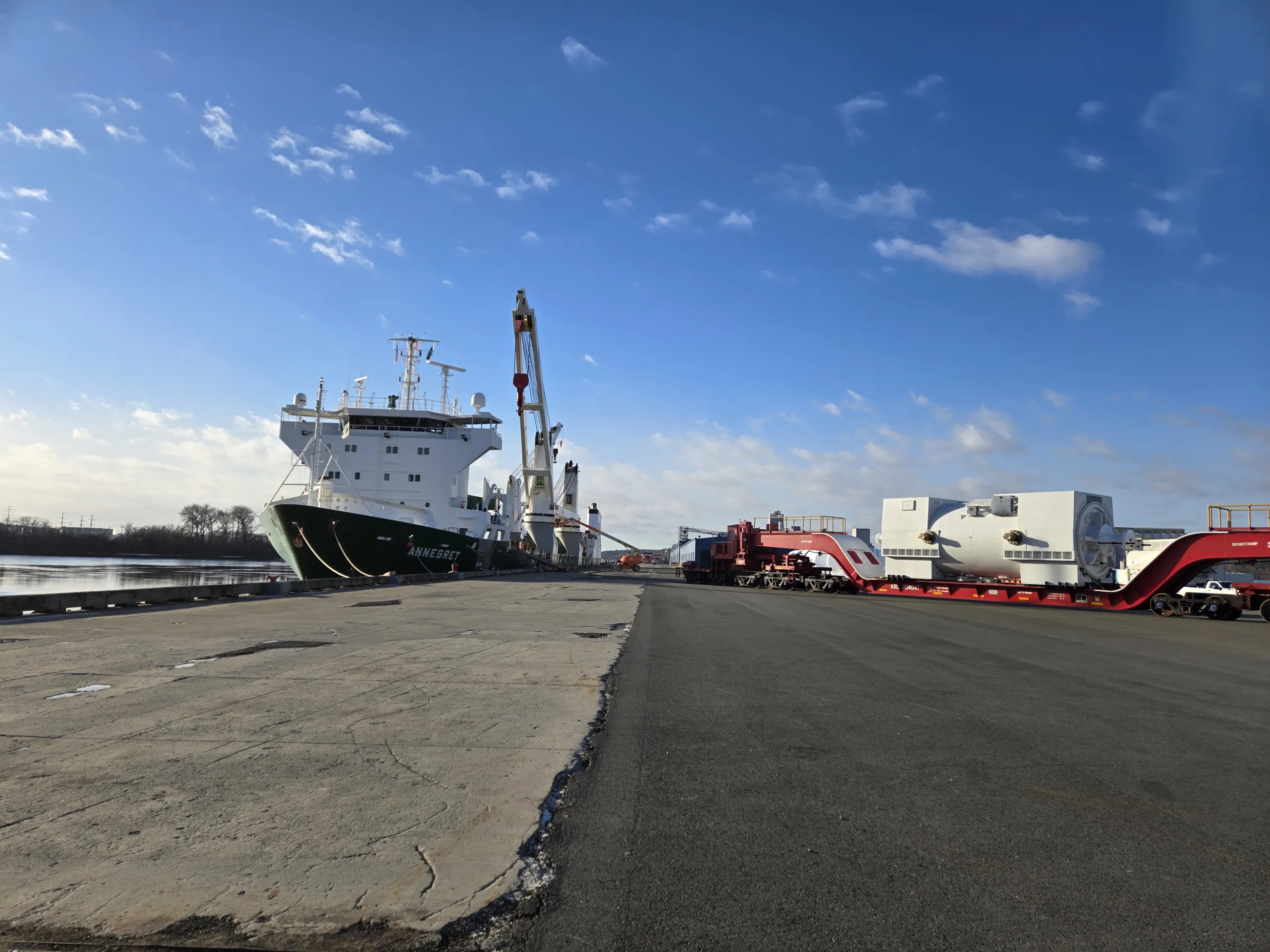 wharf with ship at dock and cargo on transport under blue sky with light clouds