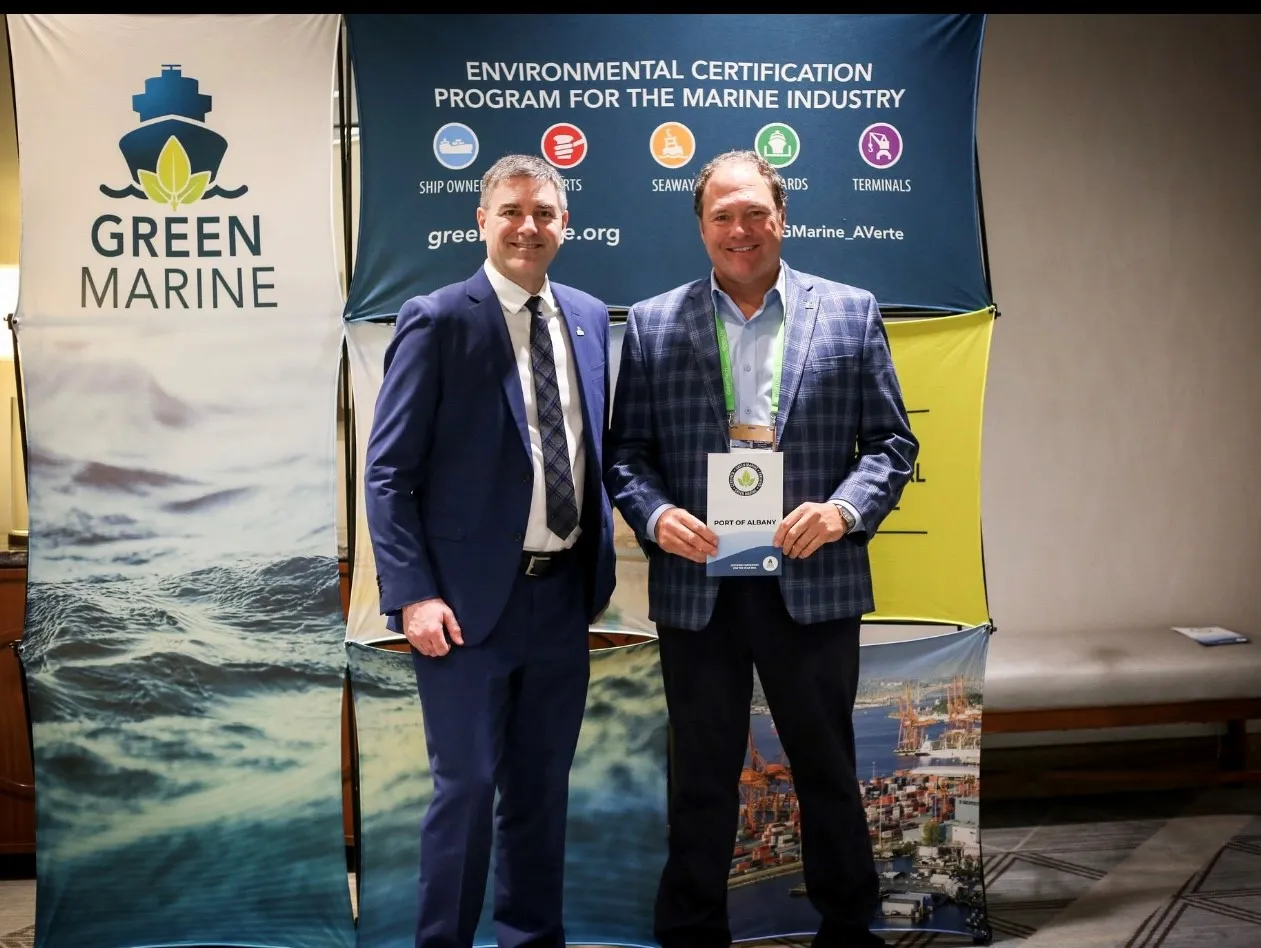 Two men standing in front of banner with Green Marine logo 